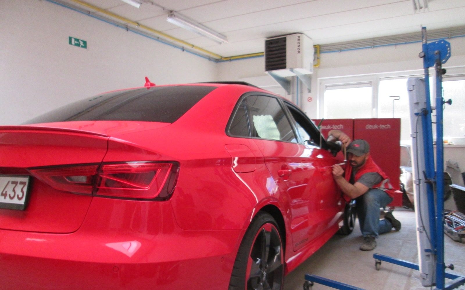 Deuk-Tech herstelt een deuk in de deur van een rode Audi zonder spuitwerk